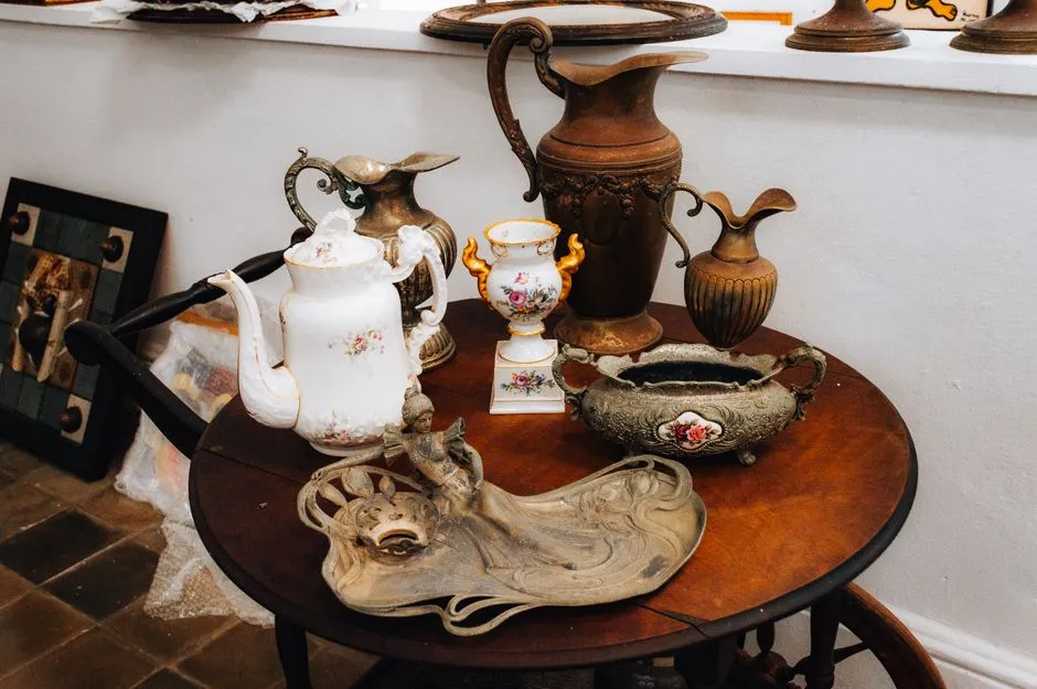 Antique porcelain and metalware staged for sale on a table