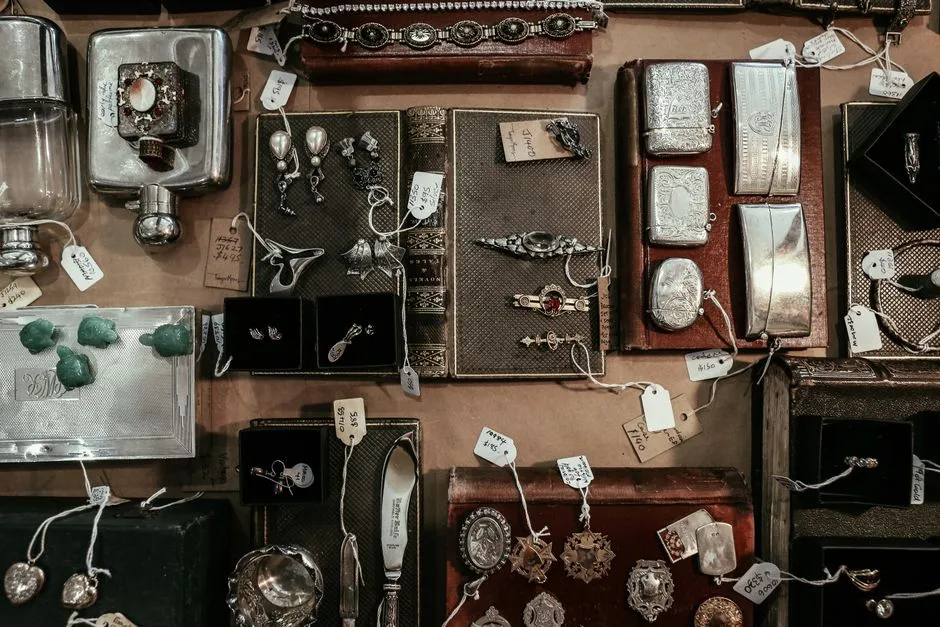 Vintage jewelry and silverware laid out with price tags at a sale